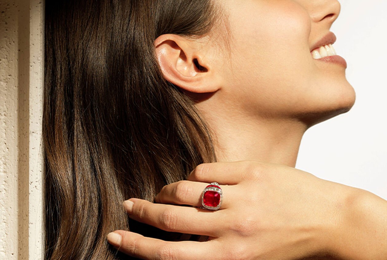Modelo luciendo el anillo Magnifica de Alta Joyería en platino con un rubí talla cojín antiguo Pigeon's Blood, rubíes talla buff-top, diamantes talla fantasía y pavé de diamantes.