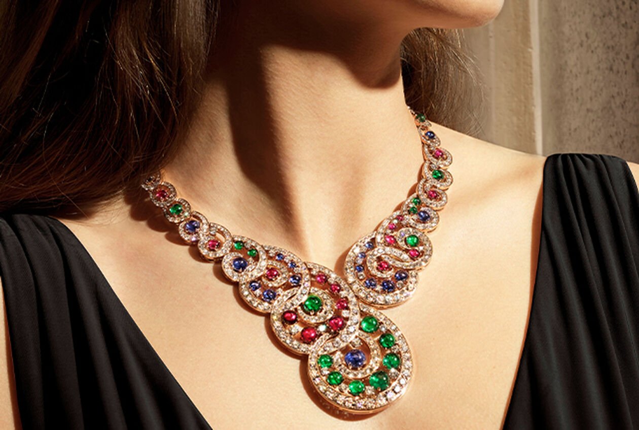 Modelo luciendo un collar Magnifica de Alta Joyería en oro rosa con esmeraldas, rubíes y zafiros talla cabujón, y diamantes.