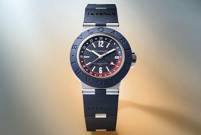 Reloj Bvlgari Aluminium GMT en aluminio con correa y bisel en caucho azul y esfera azul, fondo de cielo.